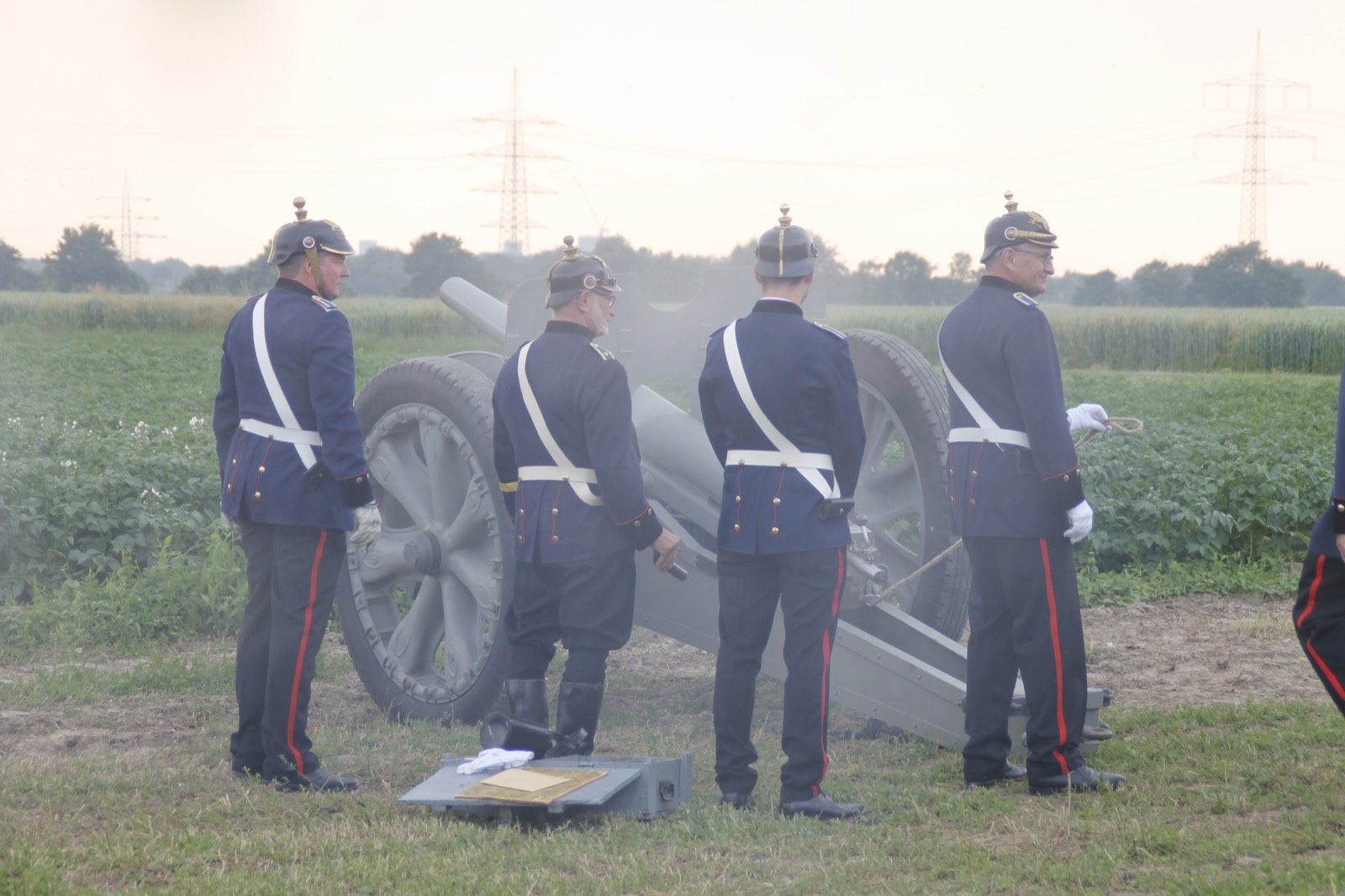 Artilleristen in Uniform am Geschütz auf einem Feld in der Abenddämmerung